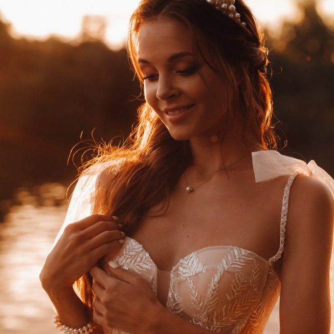 An elegant bride in a white dress enjoys nature at sunset.Model in a wedding dress in nature in the Park.Belarus.
